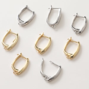 May include: A set of eight earring findings in gold and silver tones. The findings are shaped like a small hoop with a flat back.