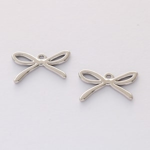 Op de afbeelding: Twee zilveren metalen strikbedels met een gat om aan sieraden of knutselwerk te bevestigen.