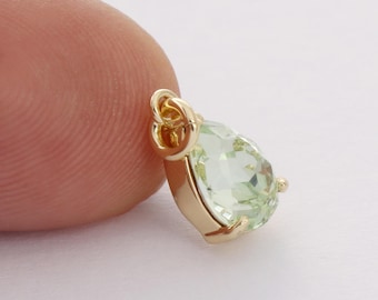 May include: A gold pendant with a pear-shaped green gemstone. The pendant has a bail for attaching to a chain.