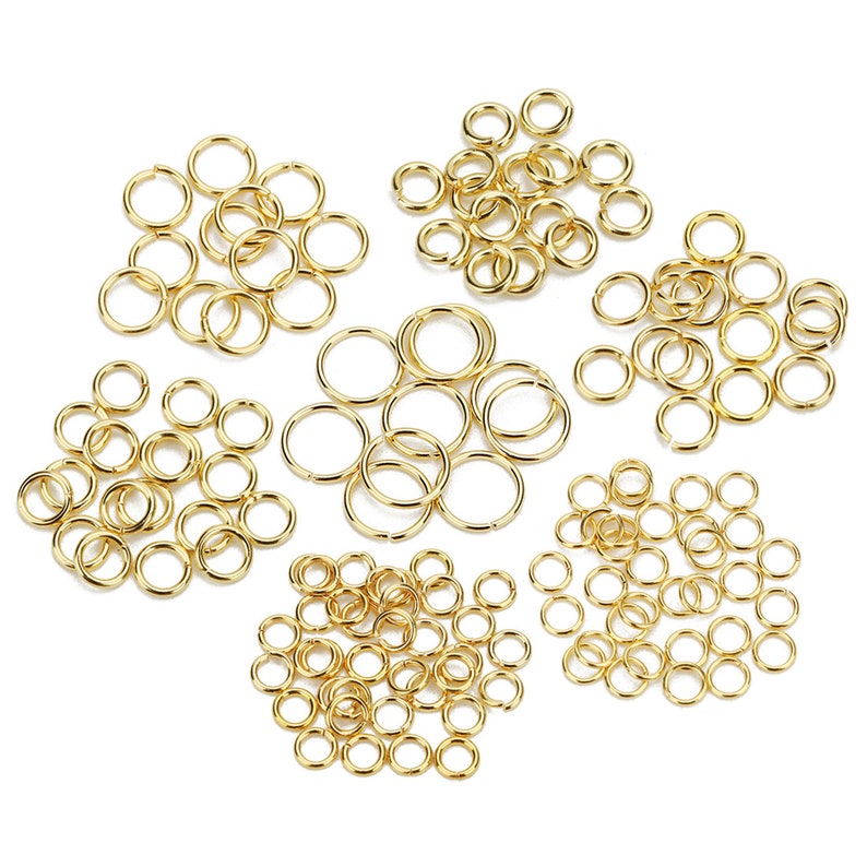 May include: A collection of gold jump rings in various sizes, perfect for jewelry making and crafting projects.