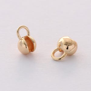 May include: Two gold-toned metal bead caps with a loop on top. The bead caps are round and have a smooth finish.