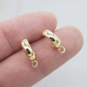 May include: Two gold-toned hoop earrings with a small jump ring hanging from each hoop.