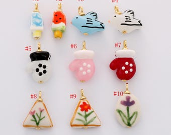 May include: A collection of ten colorful ceramic charms with gold-tone findings. Designs include an ice pop, watermelon popsicle, birds, mittens, and floral shapes. Each charm is approximately 0.75 inches in length.
