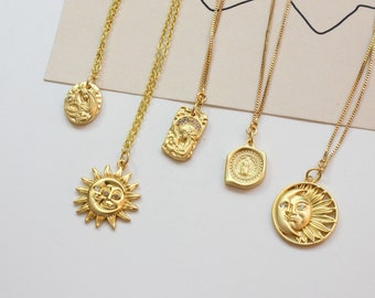 May include: Five gold necklaces with different pendants. The pendants include a sun and moon design, a religious figure, and two other abstract designs. The necklaces are on a white background.