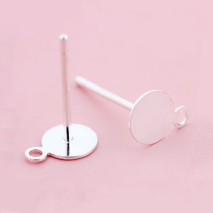May include: Two silver earring posts with round, flat, silver tops. Each top has a small loop on the side.