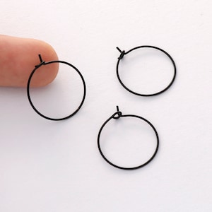 May include: Three black hoop earrings with a simple, minimalist design. The earrings are made of thin wire and have a small clasp.
