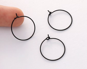 May include: Three black hoop earrings with a simple, minimalist design. The earrings are made of thin wire and have a small clasp.