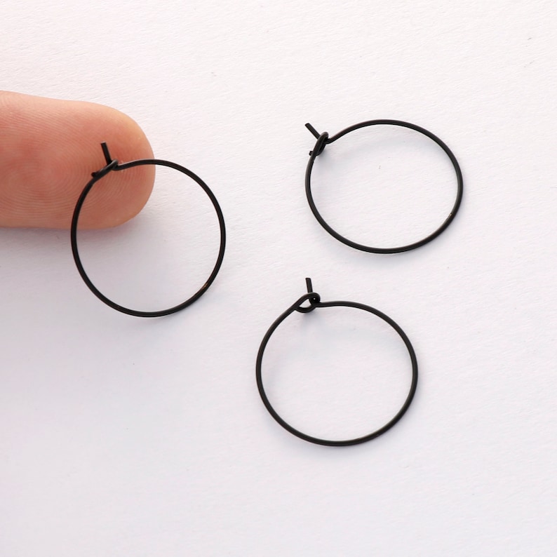 May include: Three black hoop earrings with a simple, minimalist design. The earrings are made of thin wire and have a small clasp.