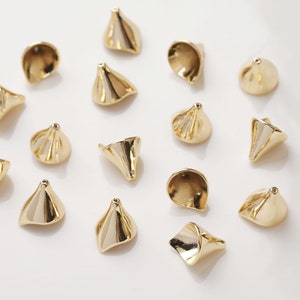 Peut inclure: Un ensemble de 15 perles en m&eacute;tal de couleur dor&eacute;e en forme de c&ocirc;ne. Les perles ont une surface textur&eacute;e et sont dispos&eacute;es sur un fond blanc.