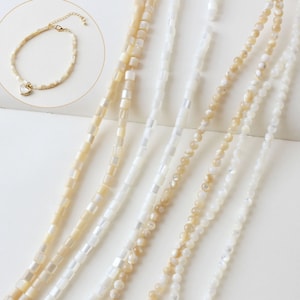 Op de afbeelding: Een set van zes kettingen gemaakt met witte en beige schelp kralen. De kettingen zijn van verschillende lengtes en hebben verschillende kraalvormen, waaronder ronde en vierkante.