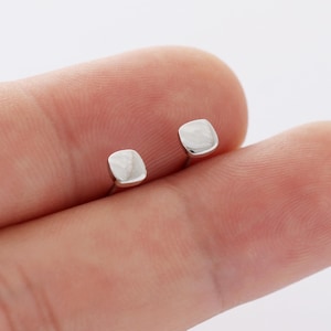 May include: A pair of silver square stud earrings. The earrings are small and simple, and they would be a great addition to any jewelry collection.