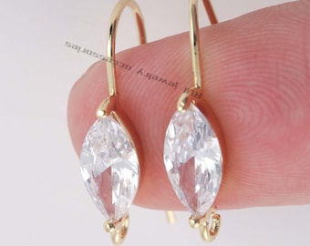 May include: A pair of gold earrings with marquise-shaped clear cubic zirconia stones. The earrings have a simple hook closure.