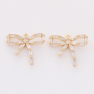 May include: Two gold-tone bow-shaped charms with clear crystal accents. Each charm has a loop at the top for attaching to jewelry.
