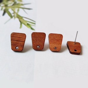 May include: Four wooden earrings with a unique shape. The earrings are a warm brown color with a visible wood grain. Each earring has a small metal accent. One earring has a post for piercing.