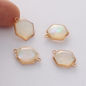 May include: Four gold-toned hexagonal charms with iridescent white shell-like inserts. Each charm has a loop for attaching to jewelry.