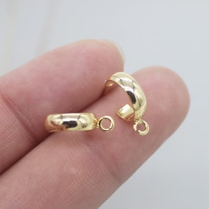 May include: Two gold-toned hoop earring findings with a jump ring attached to each. The findings are smooth and have a rounded shape.