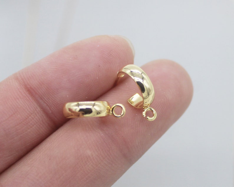May include: Two gold-toned hoop earring findings with a jump ring attached to each. The findings are smooth and have a rounded shape.