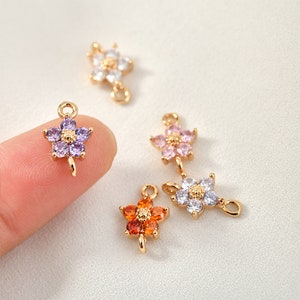May include: Five gold flower charms with different coloured rhinestones. The charms have a loop at the top for attaching to jewellery.