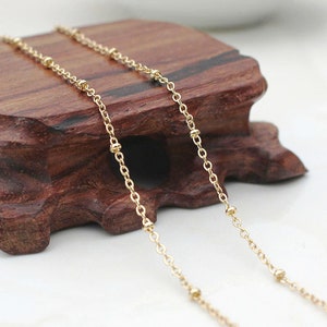 May include: A gold chain necklace with small round beads. The chain is delicate and has a simple design.