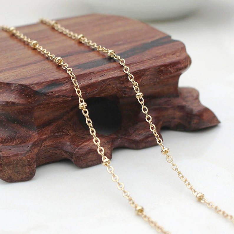 May include: A gold chain necklace with small round beads. The chain is delicate and has a simple design.