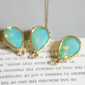 May include: Three teardrop-shaped turquoise glass beads with gold-toned metal settings. The beads have a faceted design and are strung on a chain.