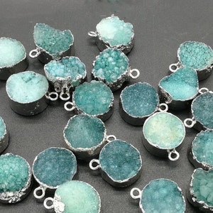 May include: Assortment of teal blue and green agate gemstone pendants with silver-toned metal settings. The pendants are round and have a textured surface.