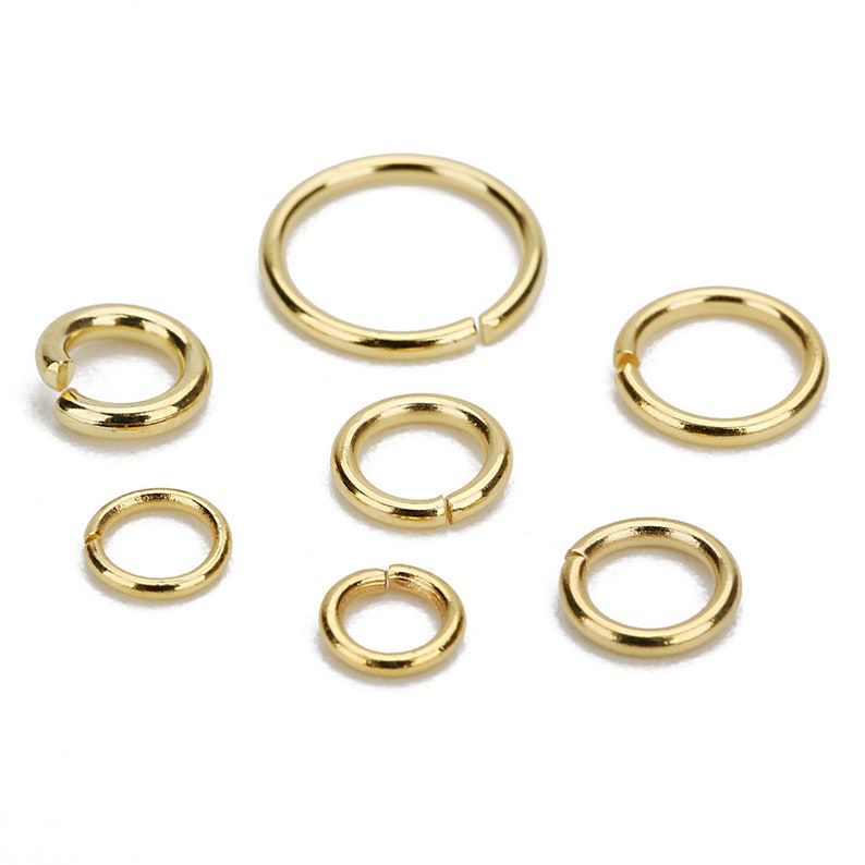 May include: Six gold jump rings of different sizes. The jump rings are smooth and shiny.