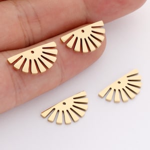 Puede incluir: Cuatro componentes de joyería dorados en forma de semicírculo. Cada componente tiene una serie de líneas rectas que irradian desde un borde curvo, que se asemejan a un diseño de sol. Hay un pequeño agujero cerca del centro de cada pieza.