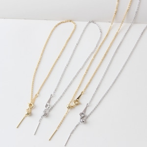 Könnte beinhalten: Drei zarte Ketten mit verstellbarer Länge. Die Ketten sind aus Silber und Gold gefertigt und haben jeweils eine kleine Kugel am Ende.