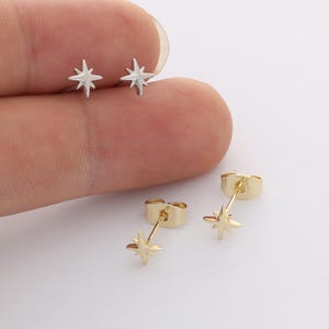 May include: Two silver-toned star-shaped stud earrings and two gold-toned star-shaped stud earrings. Each earring features a four-pointed star design with a post back. The silver earrings are positioned at the top, while the gold earrings are below.