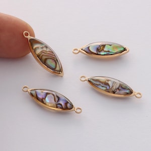 Puede incluir: Cuatro abalorios de metal dorado con incrustaciones de nácar de abulón. Cada abalorio tiene forma de lágrima y un bucle para sujetarlo a joyas.