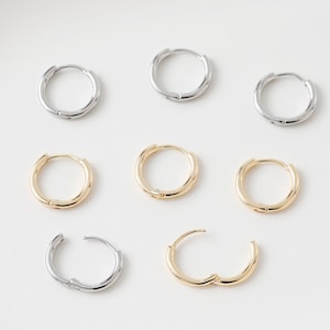 May include: Set of six hoop earrings in silver and gold tones. The earrings are simple and classic, with a smooth finish.