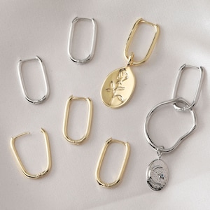 May include: A set of six gold and silver hoop earrings. Two of the earrings have charms attached. One charm features a rose and the other a crescent moon.