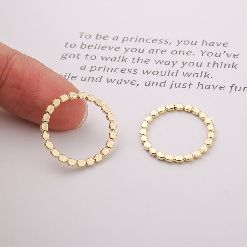Puede incluir: Dos anillos dorados con un dise&ntilde;o texturizado hexagonal. Los anillos son simples y delicados.