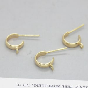May include: Three gold-toned earring hoops with a small loop at the bottom and a straight pin attached to the top.