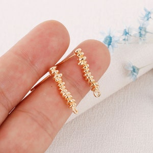 May include: A pair of gold-toned earring findings with a beaded design. The findings have a loop at the end for attaching earrings.