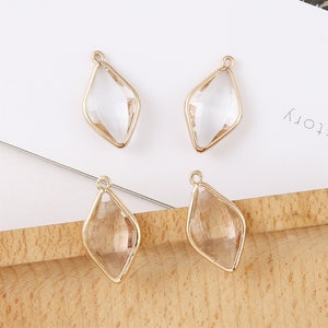 Op de afbeelding: Vier gouden metalen oorbelcharms met heldere glazen diamantvormen. De charms hebben een lus aan de bovenkant om aan oorbellen te bevestigen.