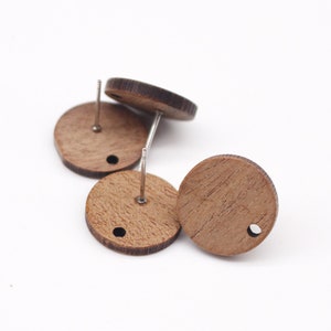 May include: Three round wooden earring blanks with silver posts. The blanks are a light brown color and have a small hole in the center.