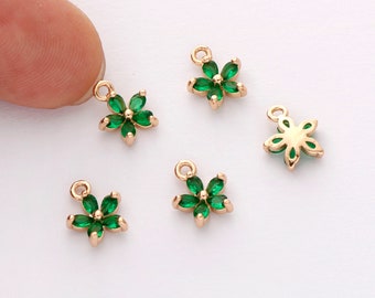 May include: Five gold-tone flower charms with green crystal accents. Each charm has a loop for attaching to jewelry.