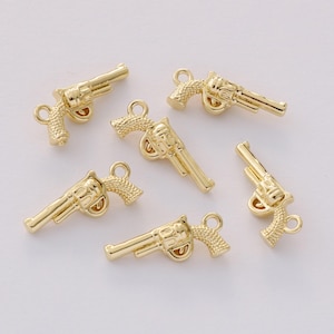 May include: Gold-colored revolver charms. These small, detailed charms feature a classic revolver design with a loop for attaching to jewelry or other crafts. The charms are made of a shiny, metallic material.