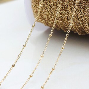May include: Gold chain with small beads, perfect for jewelry making. The chain is shown in three strands, with the beads spaced evenly.