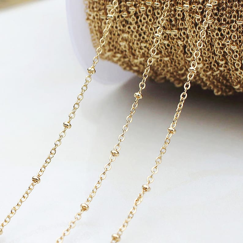 May include: Gold chain with small beads, perfect for jewelry making. The chain is shown in three strands, with the beads spaced evenly.