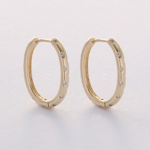 May include: A pair of gold hoop earrings with small clear stones set around the edge.