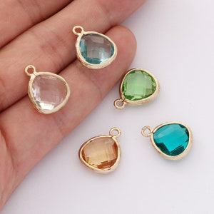 May include: Five gold-tone pendant charms with faceted glass stones in various colors: clear, light blue, green, and teal.