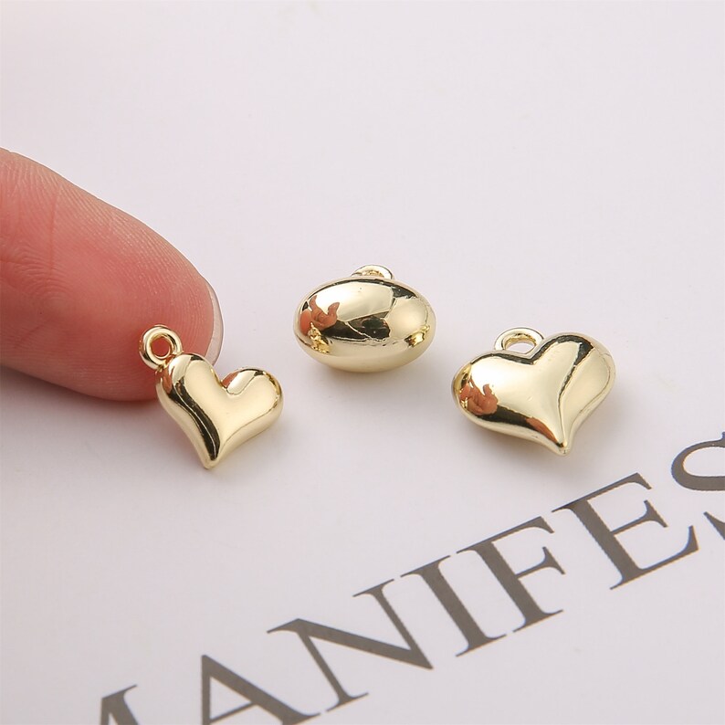 Puede incluir: Tres abalorios de metal de color dorado: un coraz&oacute;n, un &oacute;valo y otro coraz&oacute;n. Los abalorios tienen un acabado brillante y son adecuados para la elaboraci&oacute;n de joyas.