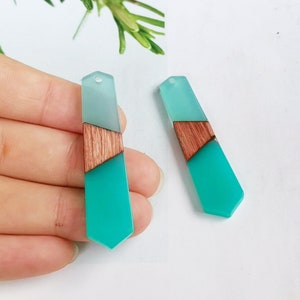 Peut inclure: Deux boucles d'oreilles pendantes en résine turquoise et bleu clair avec un accent en bois. Les boucles d'oreilles sont en forme de goutte d'eau avec un fond pointu.