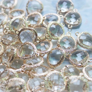 May include: A close-up of a group of clear glass beads with gold-toned metal accents. The beads are round and have a faceted design. They are perfect for jewelry making or other craft projects.