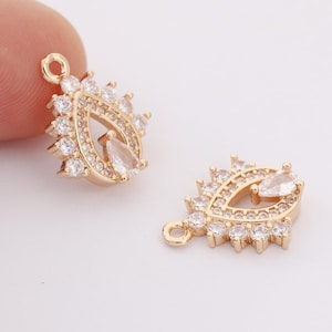 Peut inclure: Deux breloques pendantes dorées en forme de larme avec des embellissements en cristal transparent. Les breloques ont une boucle en haut pour être attachées à un collier ou un bracelet.