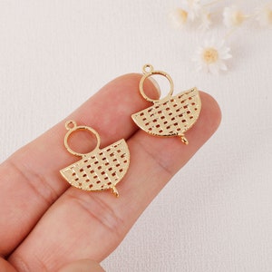 May include: Two gold-colored metal charms. Each charm features a semi-circular woven design with a small loop at the top and a small loop at the bottom. The charms are designed for jewelry making.