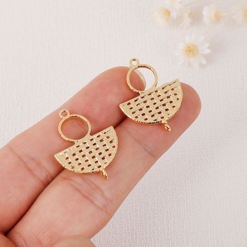 May include: Two gold-colored metal charms. Each charm features a semi-circular woven design with a small loop at the top and a small loop at the bottom. The charms are designed for jewelry making.